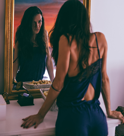 Sexy girl in nightgown looking at reflection in a mirrorの写真素材