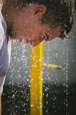Man taking a shower outside and looking downの写真素材