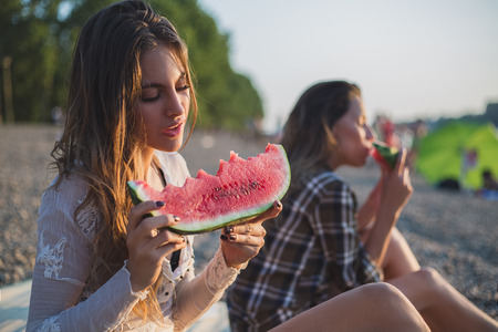 Girlfriends eating watermelon on the beach. Sunsetの写真素材