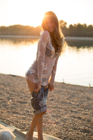 Girl putting on clothes at the beach. Sunsetの写真素材