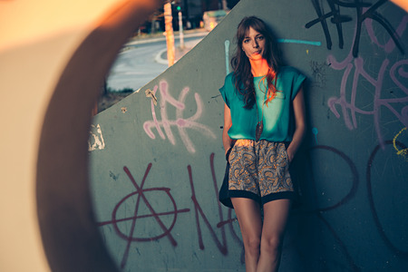 Girl leaning on graffiti wall. Sunsetの写真素材