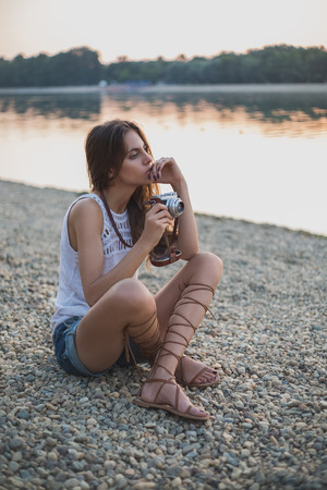 Girl holding camera and thinking. Sunsetの写真素材