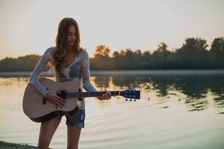 Girl playing guitar on the beach. Sunsetの写真素材