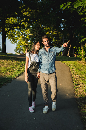 Couple walking in the park. He is showing something to herの写真素材