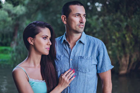Couple standing by the river, hugging and looking far