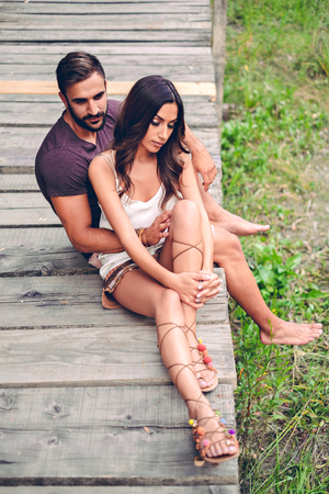 Couple sitting at the pier and thinking. Sunset sceneの写真素材