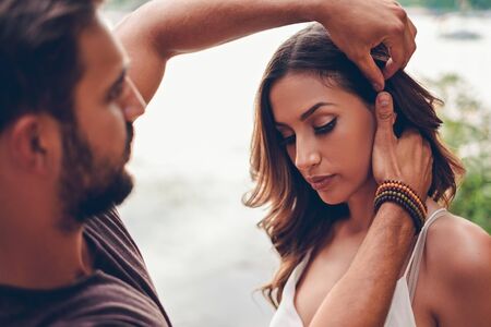 Man is fixing girls hair by the waterの写真素材