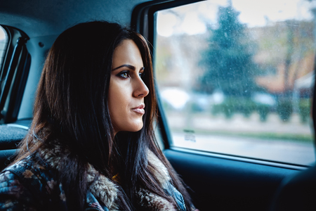 Sad girl looking through car windowの写真素材