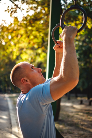 Man looking at gymnastics rings in the park and preparing to workoutの写真素材