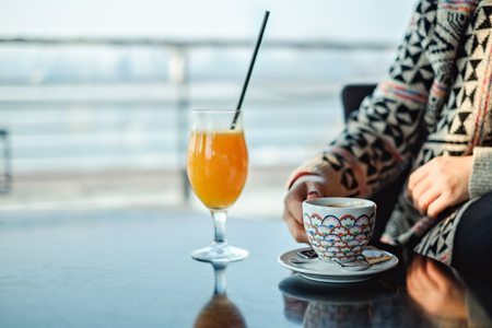 Female picking up coffee in a coffee shop.  Orange juice on the tableの写真素材