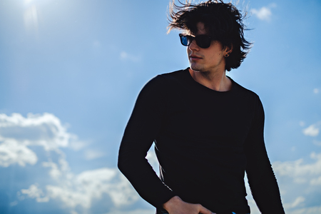 Man in the sun looking to the side with sky in the backgroundの写真素材