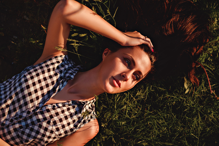 Girl lying in the grass and enjoying the sun while holding her hairの写真素材
