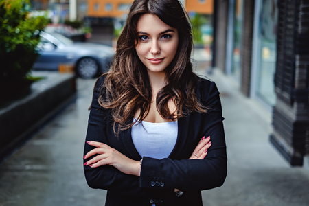 Confident business woman looking at the camera while standing on the street with hands crossedの写真素材
