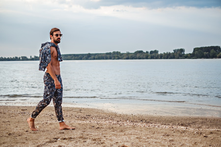 Shirtless fit man walking on the beachの写真素材