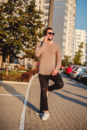 Happy man leaning on the street light talking on the phoneの写真素材