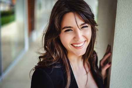 Portrait of a beautiful brunette laughing by the wall and looking in to a cameraの写真素材