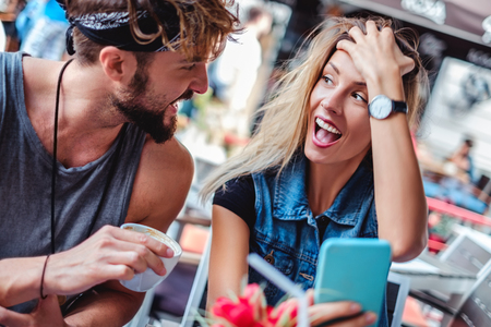 Girl is shocked with what she heard from boyfriend while she holds the mobile phone in a coffee shopの写真素材