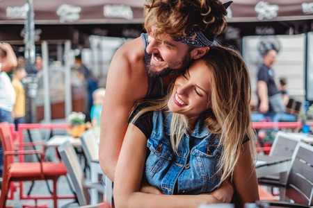 Boyfriend hugging girlfriend in a coffee shop and they are smilingの写真素材