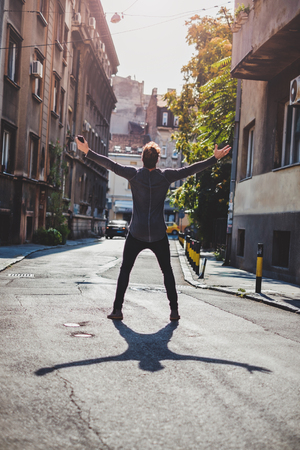 Hipster holding arms wide open in the street. He is celebratingの写真素材
