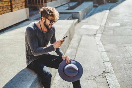 Excited hipster looking at mobile phone. He is surprised.の写真素材
