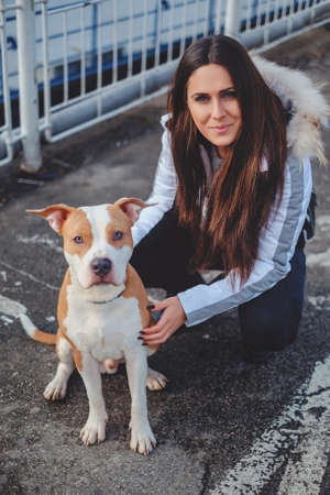 Girl posing outside with her dog on a cold day. Both looking at the camera
