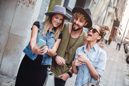 Friends taking selfie on the street and laughing. Beautiful summer dayの写真素材