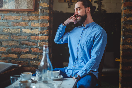 Hipster man imitating cell phone conversation in a cafe while drinks are on the tableの写真素材