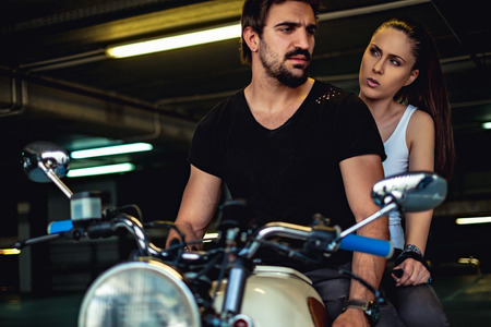 Angry girlfriend talking to her biker boyfriend in a garage while riding a motorcycleの写真素材