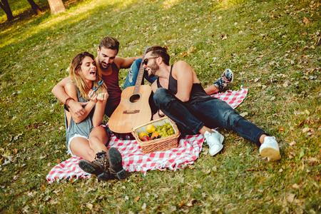Friends hugging and smiling on a picnic blanketの写真素材