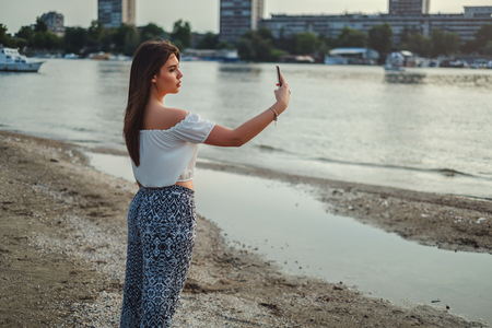 Beautiful brunette girl taking selfie on the beachの写真素材