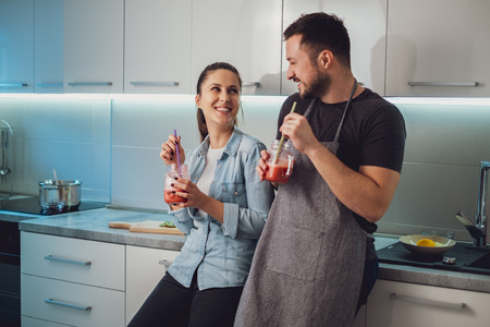 Husband and wife having fun with smoothie in the kitchen and looking at each otherの写真素材
