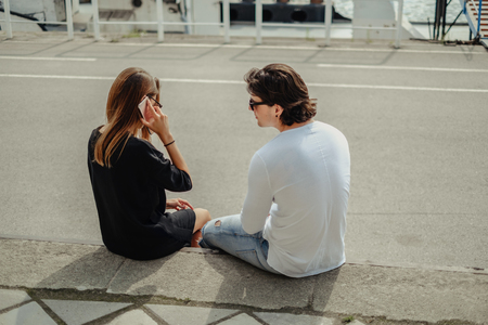 Girl talking on the phone while boyfriend is waiting. Beautiful sunny dayの写真素材