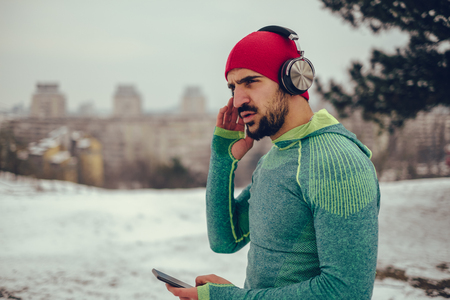 Smiling athletic man listening music in his workout on snowy winter day.の写真素材