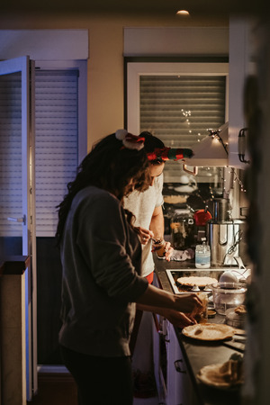 Happy couple preparing pancakes in the kitchen on new years eveの写真素材