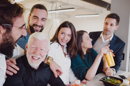 Smiling coworkers having fun while having lunch in the cafeteria