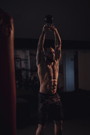 Muscular bearded man lifting kettle bell in the gymの写真素材