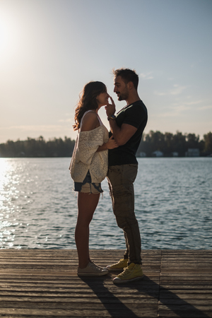 Handsome man touching his smiling girlfriends nose by the river on a sunny dayの写真素材