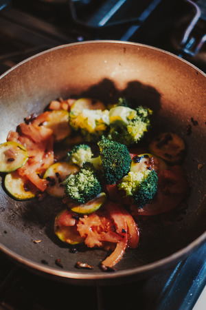 Mixed vegetables cooking in oil in the frying pan on the gas stoveの写真素材