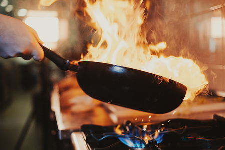 Chef steering flamed frying pan in the kitchenの写真素材