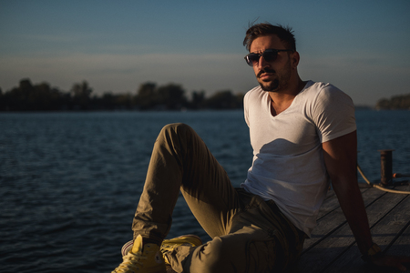 Serious handsome man thinking by the river on a sunny dayの写真素材