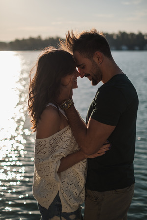 Happy smiling couple in love touching heads by the river in sunset. Beautiful autumn dayの写真素材