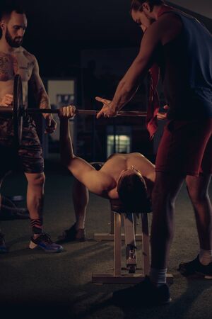 Man helping his friend doing bench press in the gymの写真素材