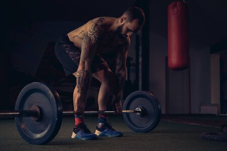 Tattooed male athlete start lifting weight from the floorの写真素材