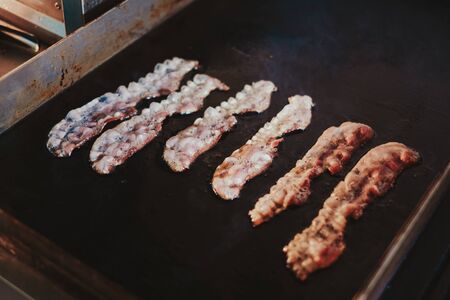 Pork bacon frying on the kitchen grillの写真素材