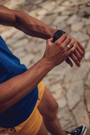 Man holding smartwatch outdoors on a sunny dayの写真素材