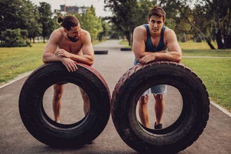 Tired muscular men resting from flipping tires in the parkの写真素材