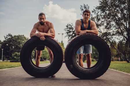 Male athletes resting from a workout with tires in the park