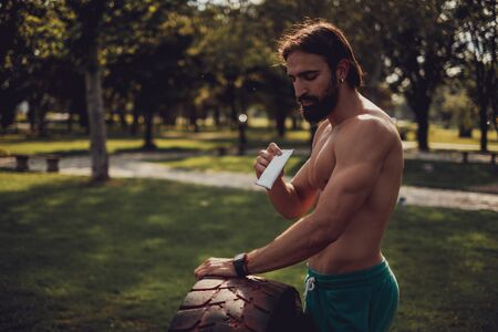 Handsome man eating protein bar after hard workout in the park