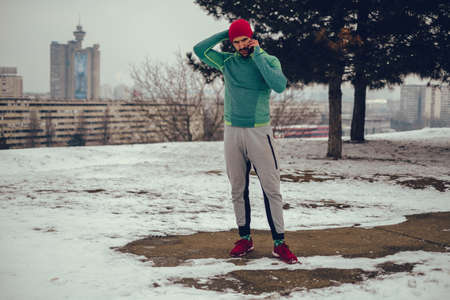 Worried athletic man talking on the mobile phone outside on a winter dayの写真素材