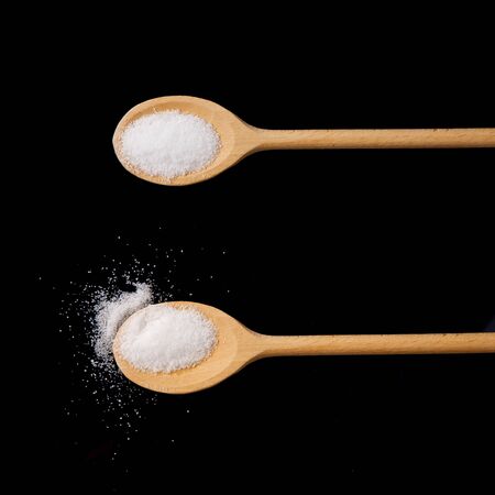 sugar in a wooden spoon isolated on black backgroundの写真素材